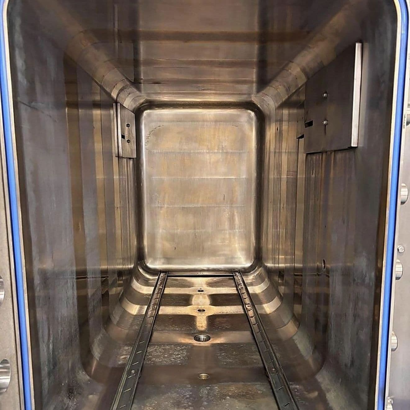 A larger sterilizer chamber with staining on the walls and floor before cleaning