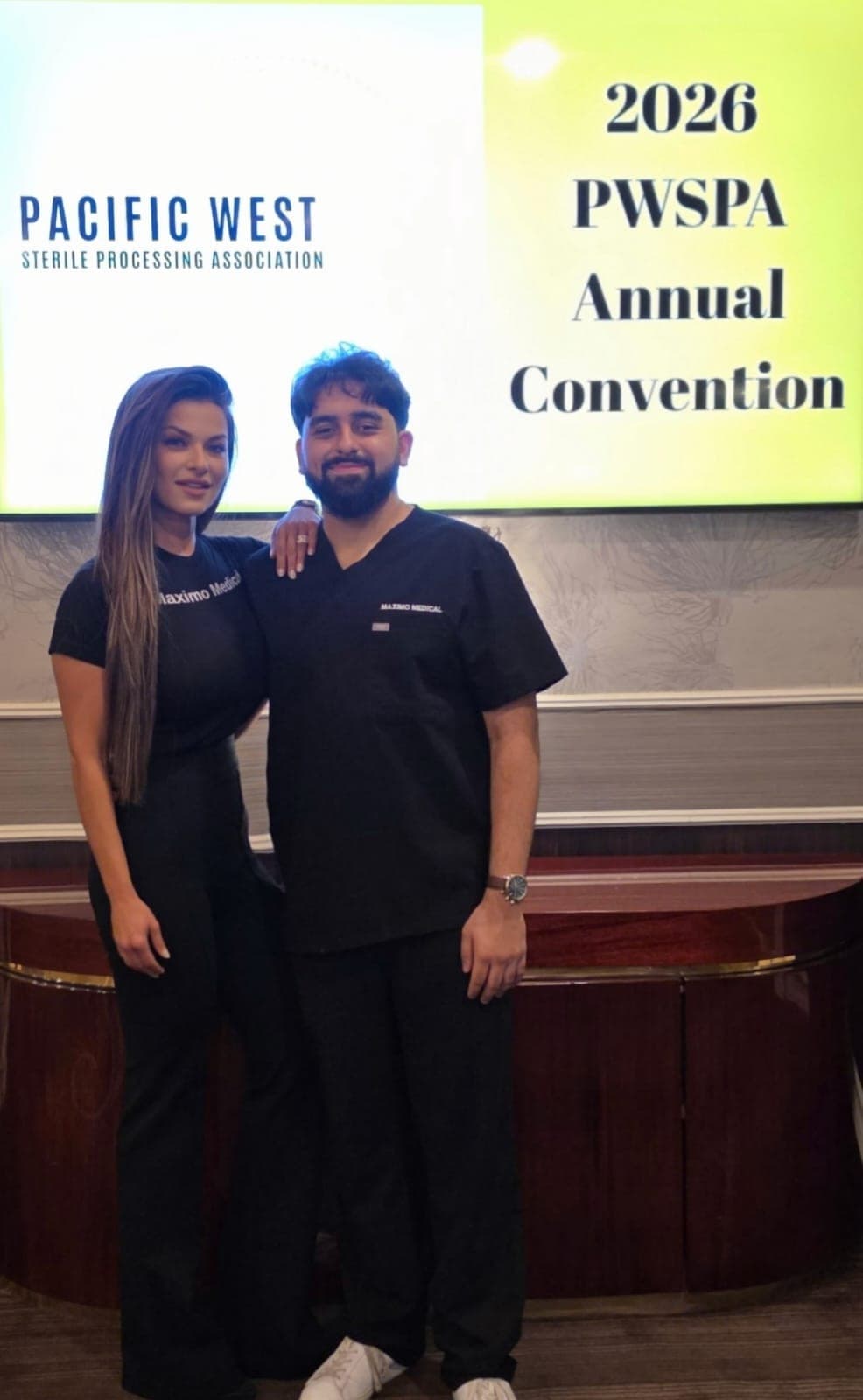 Two Maximo Medical team members in front of the Pacific West Sterile Processing Association 40th Annual Convention signage in Las Vegas
